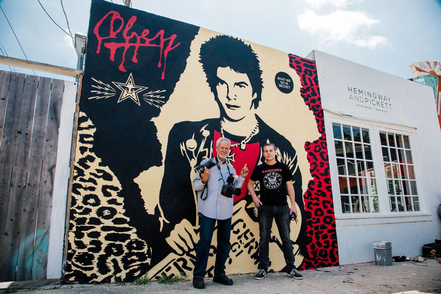 Shepard Fairey und Gary Leonard stehend vor einem vor Mural