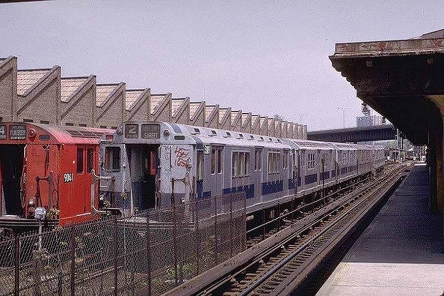Historisches Farbfoto eines U-Bahn-Zugs in New York mit frühen Graffiti-Tags und Schriftzügen auf den Waggons, die die Ausbreitung der Kunstform auf öffentlichen Verkehrsmitteln zeigen.
