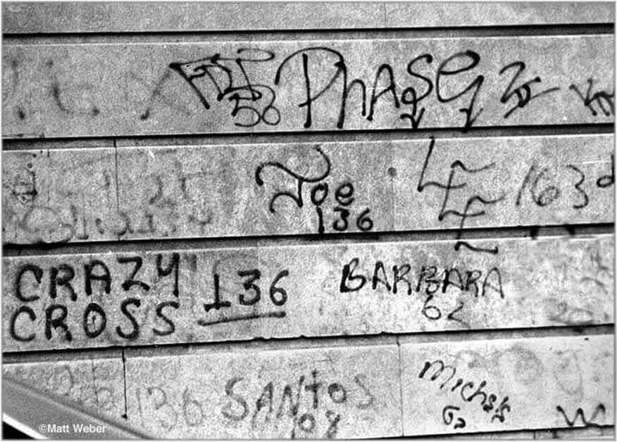 Historisches Schwarz-Weiß-Foto von frühen Graffiti-Tags, darunter der Schriftzug des berühmten New Yorker Pioniers Phase 2, auf einer Wand