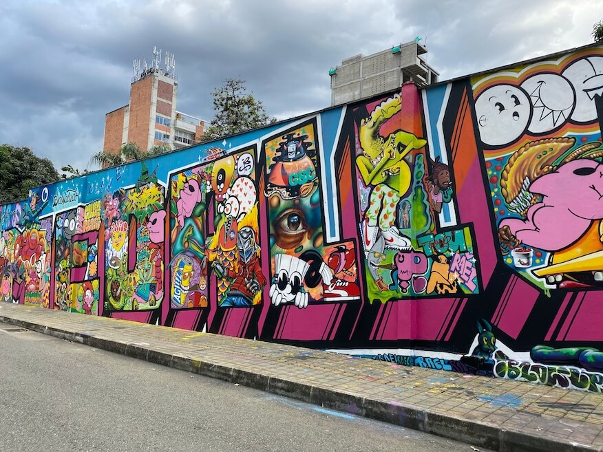 Farbenfrohes, großes Wandgemälde in Südamerika, das komplexe Graffiti-Schriftzüge und Comic-ähnliche Figuren zeigt.